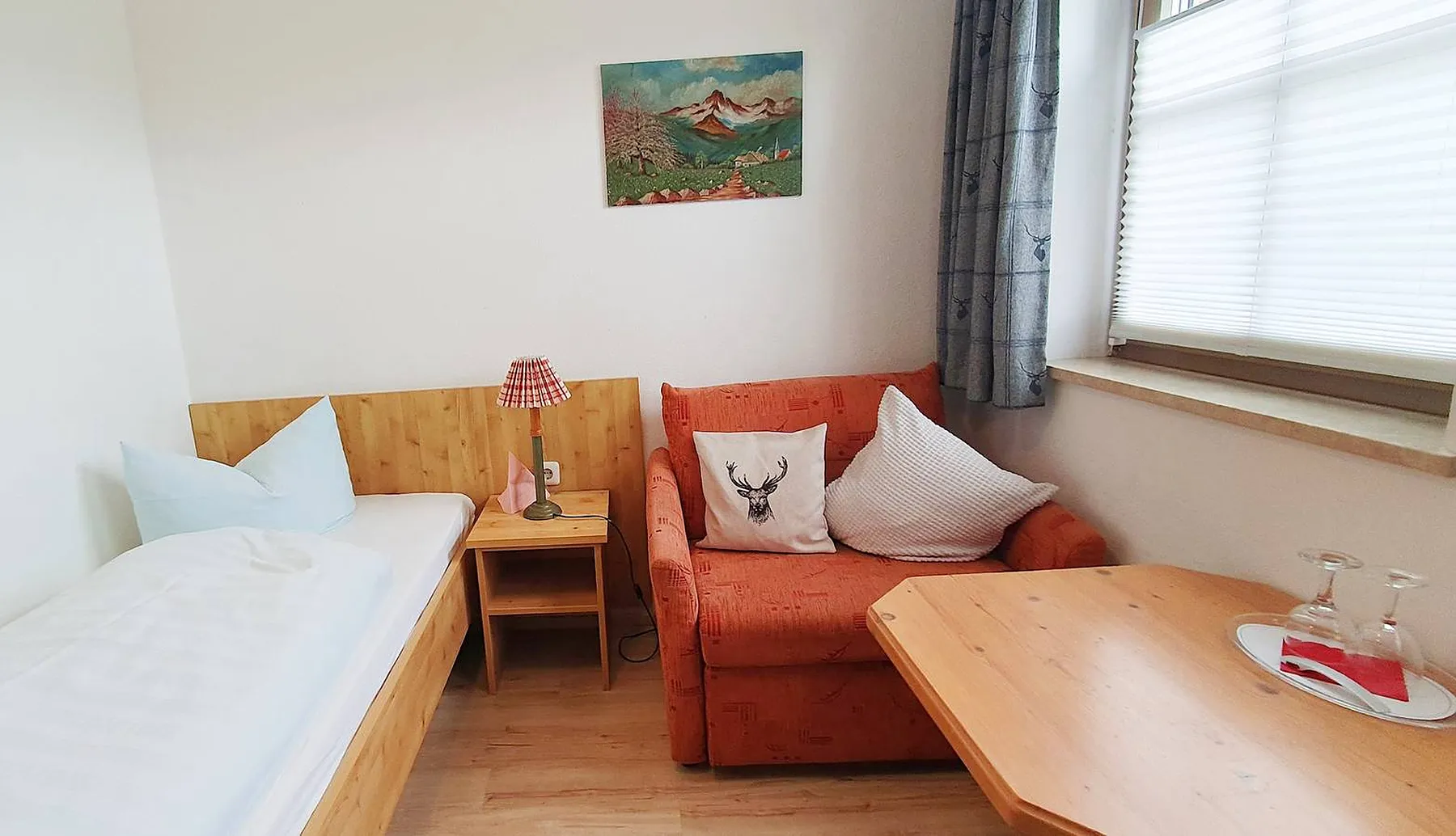 Zimmer mit Einzelbett, Sessel und Tisch